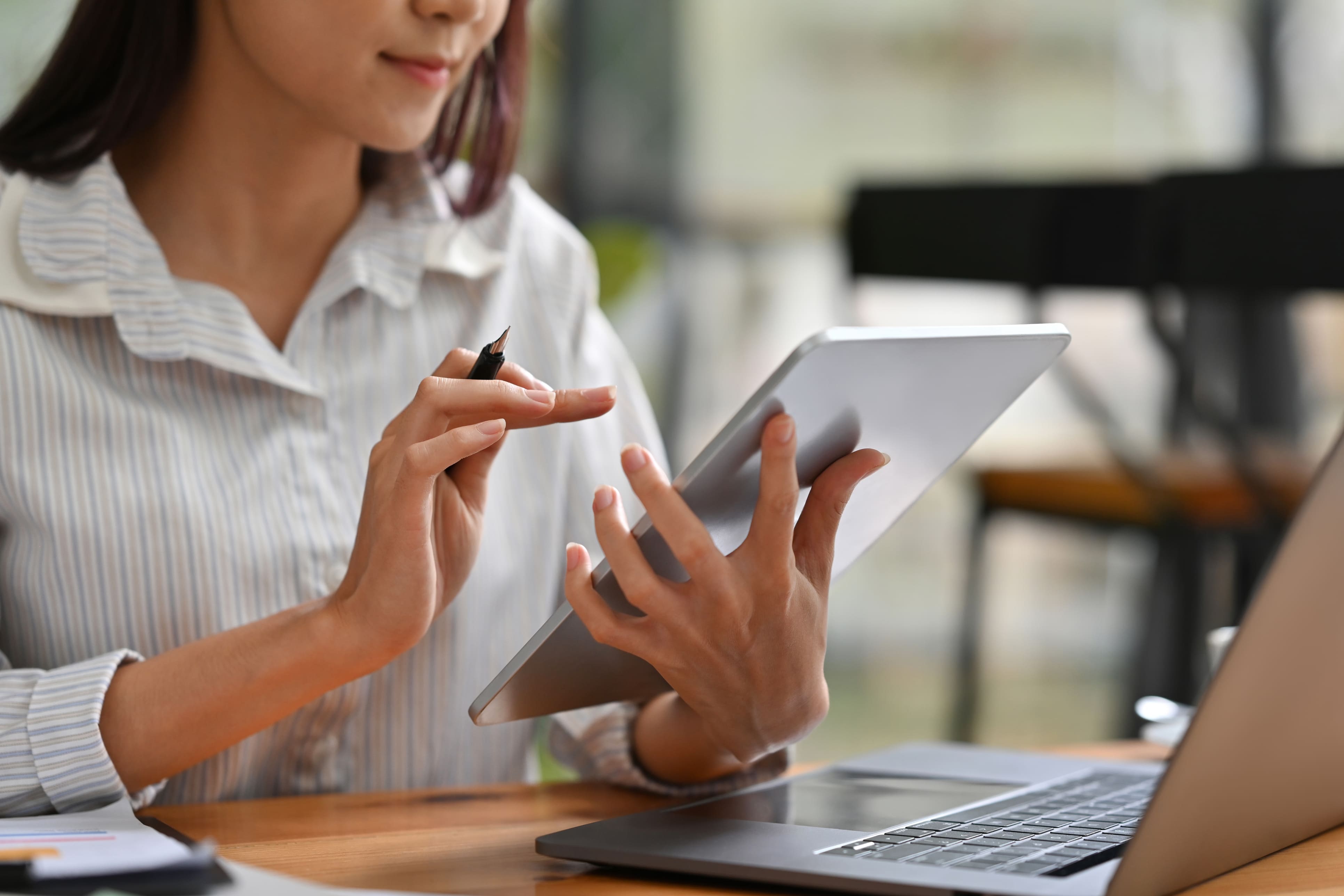 Síndica utilizando tablet e notebook para acessar sistema digital de gestão condominial.
