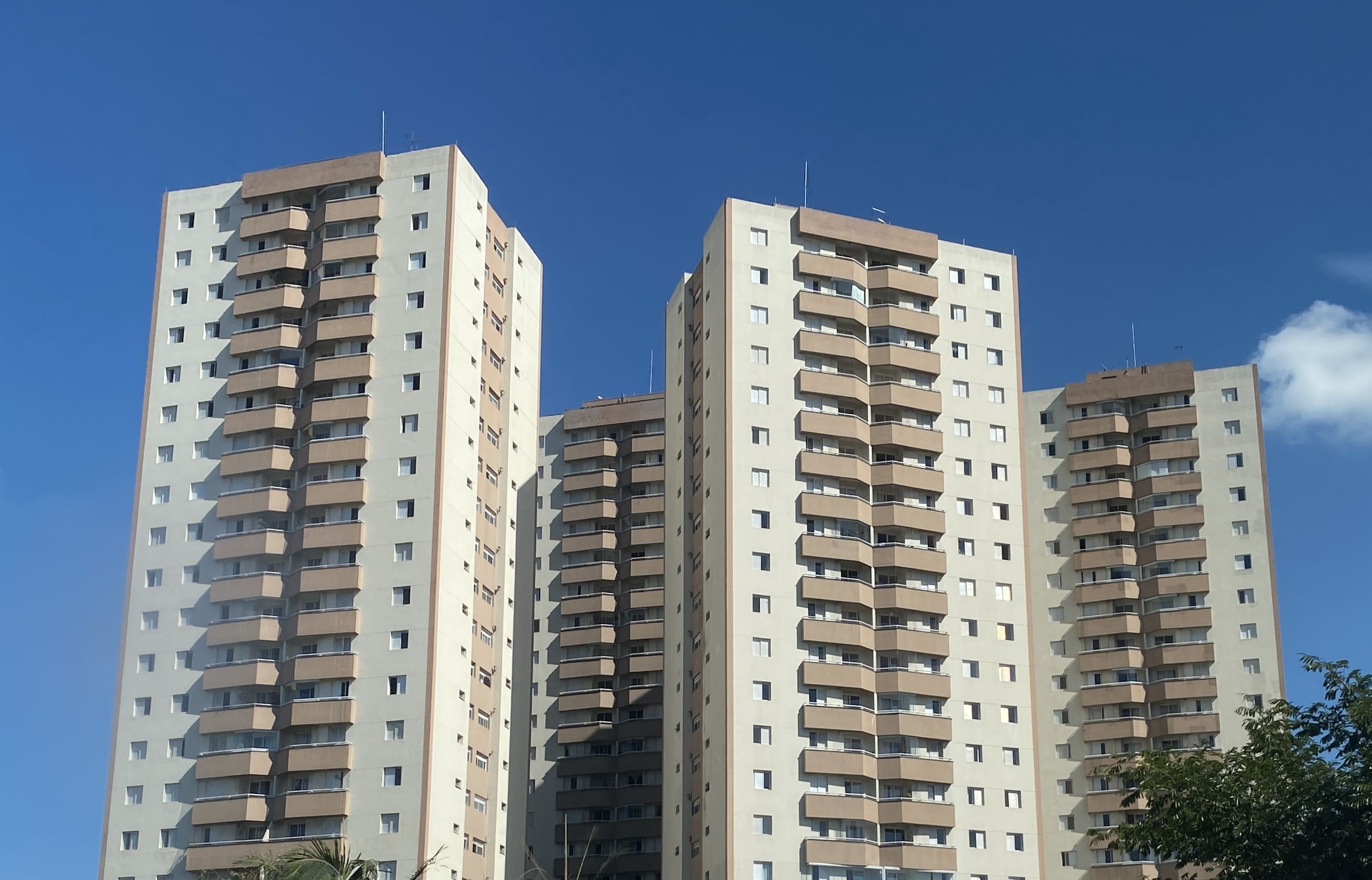 Conjunto de edifícios residenciais modernos contra o céu azul, representando condomínios urbanos.